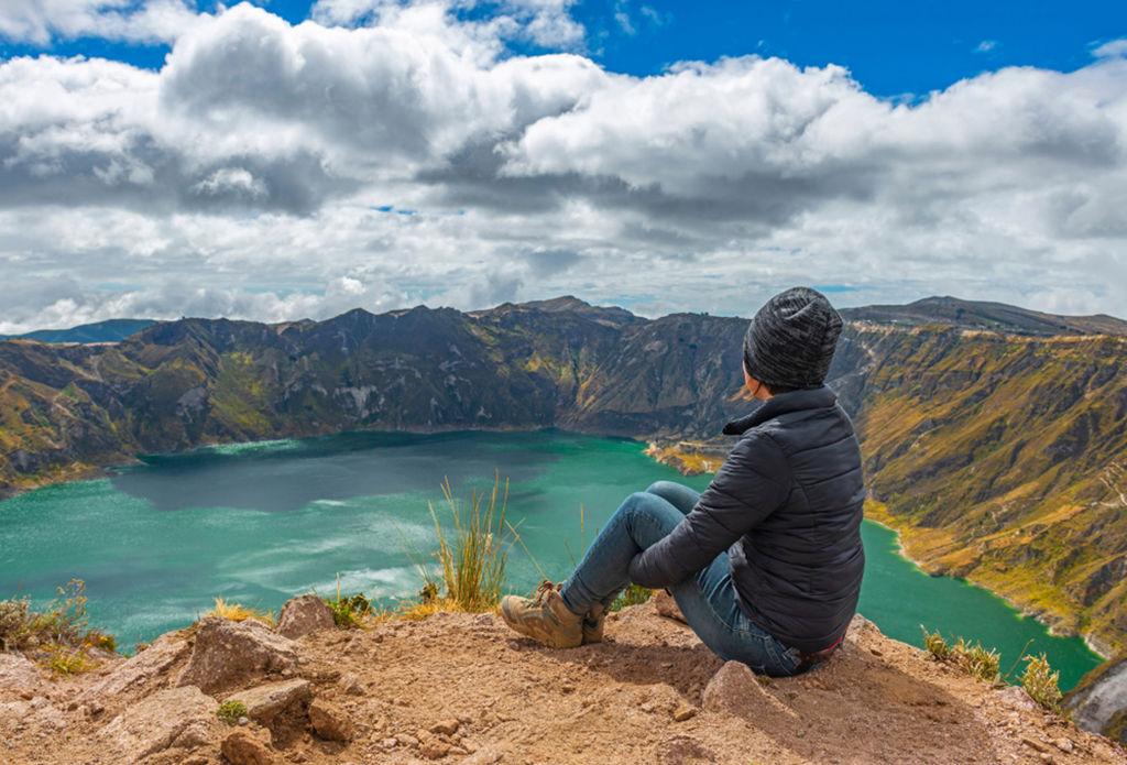 Reiziger kijkt uit over het Quilotoa-kratermeer in Ecuador tijdens een groepsrondreis.