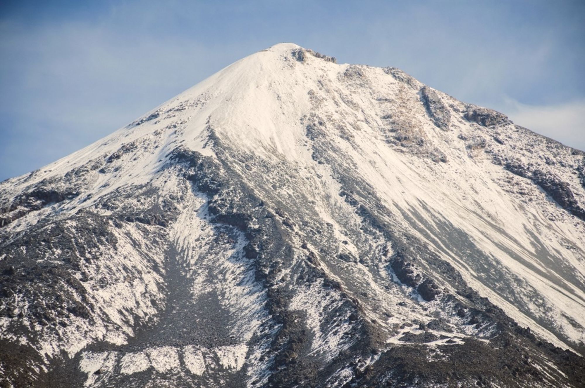 Besneeuwde top van de Popocatépetl-vulkaan in Mexico, met rotsige hellingen onder een heldere lucht.
