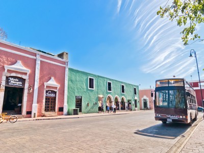 Gekleurde gevels en stadsbus op het plein van Valladolid, route Mexico.