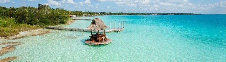 Houten steiger met rieten hutje in het turquoise water van Laguna Bacalar, Mexico.
