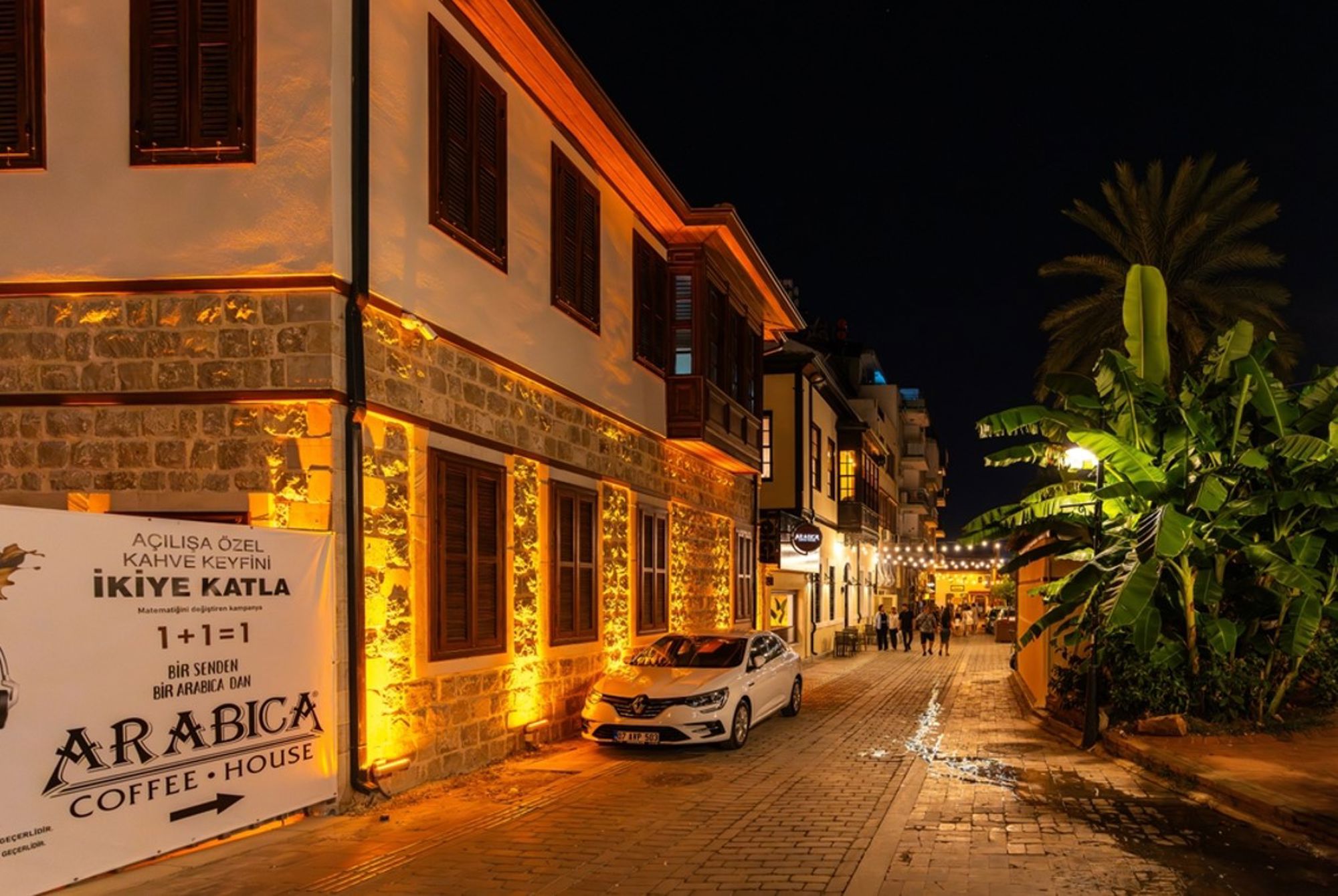 Verlichte straat in de oude binnenstad van Antalya, met Ottomaanse huizen en palmbomen in de avond.