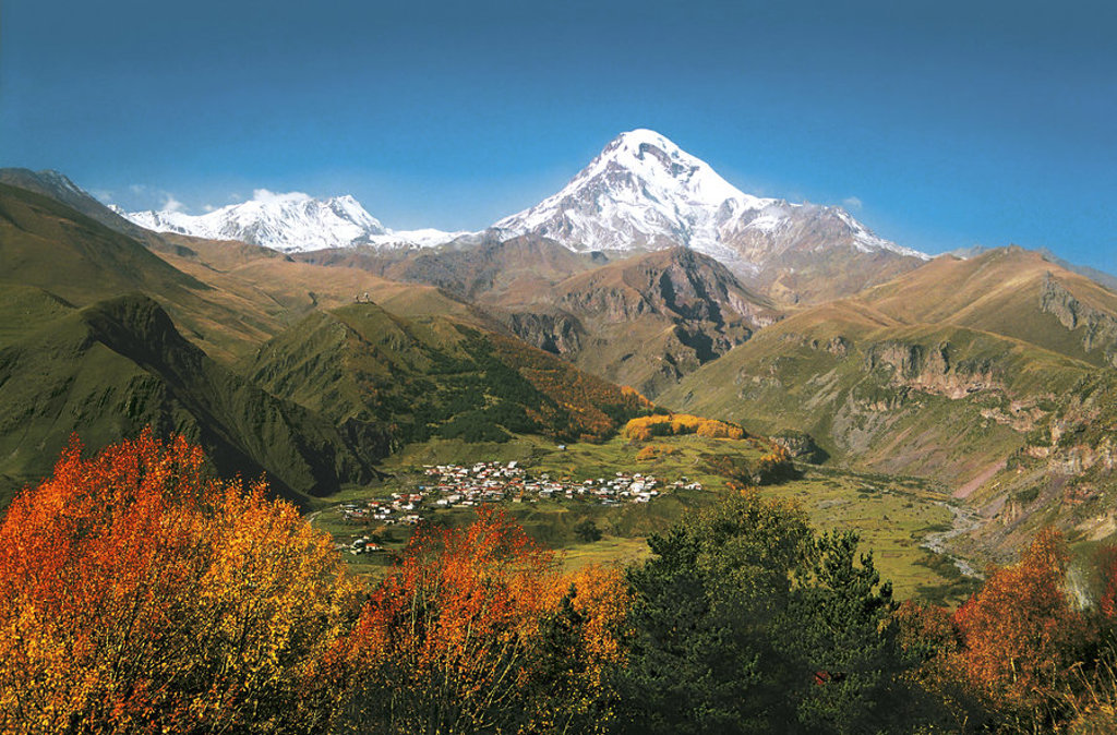 Uitzicht op de besneeuwde berg Kazbek en een bergdorp in de Georgische Kaukasus tijdens een familiereis.
