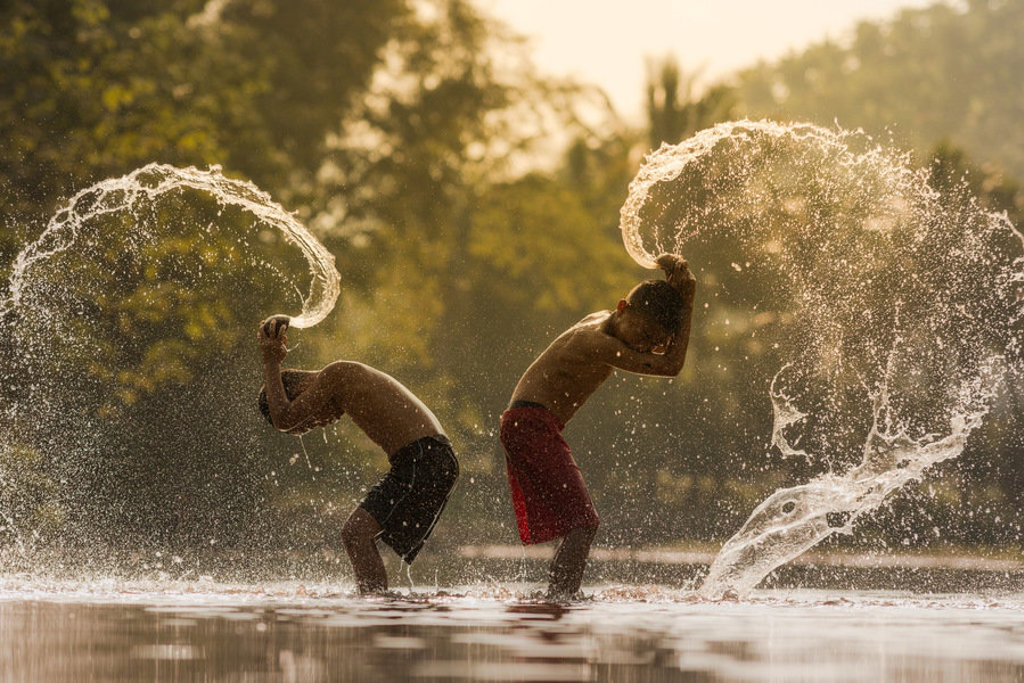 Kinderen spelen in een rivier in Vietnam en maken grote waterspetters tijdens een familiereis.