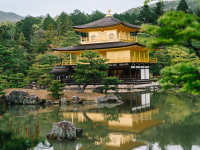 Gouden Paviljoen Kinkaku-ji in Kyoto, weerspiegeld in de vijver tussen dennen en rotsen.