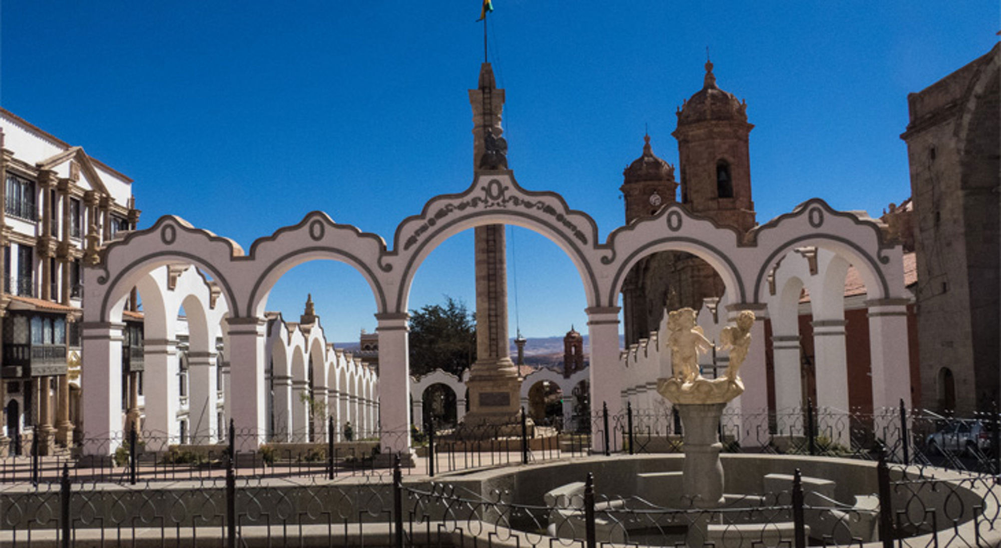 Witte bogen bij Plaza 10 de Noviembre met fontein en kathedraal in Potosí, Bolivia.