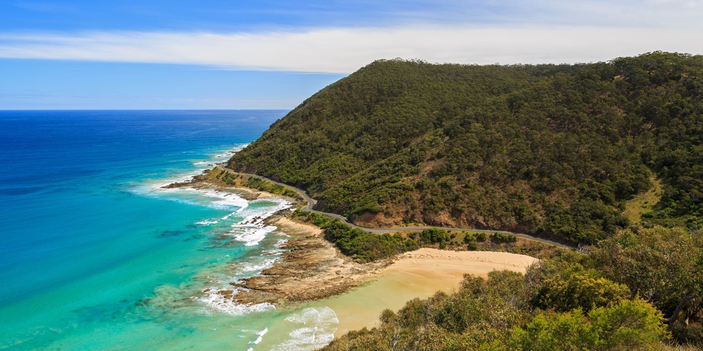 Kustweg langs groene heuvels en turkooisblauwe zee tijdens groepsrondreis Australië van Sydney naar Darwin.