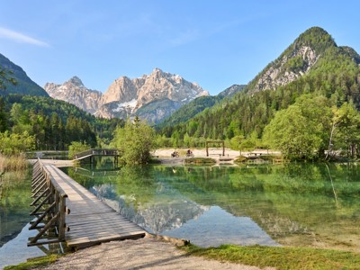 Houten brug bij het Jasna-meer met uitzicht op de Julische Alpen in Slovenië.