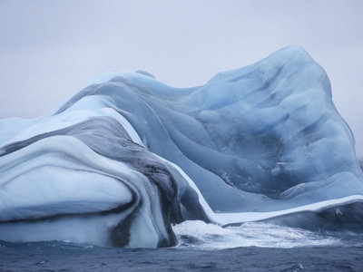 Blauwe ijsberg met donkere strepen in de oceaan bij Antarctica en South Georgia.