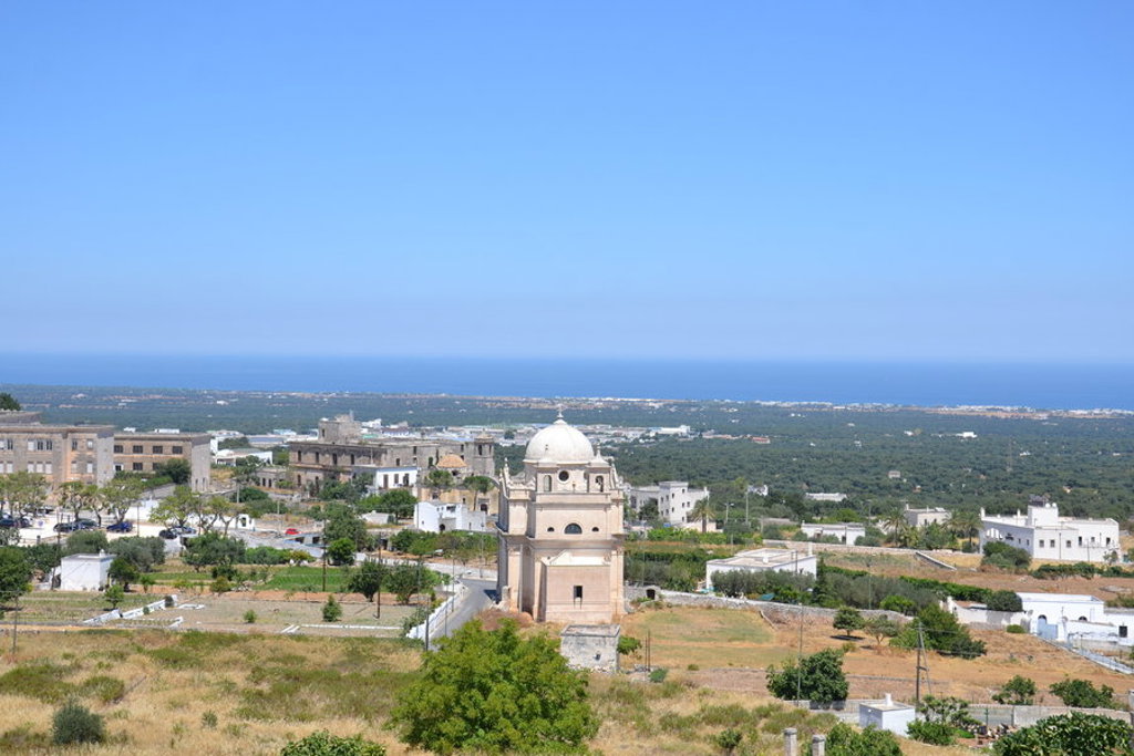 Uitzicht over het landschap van Puglia met een kerk en de Adriatische Zee op de achtergrond.