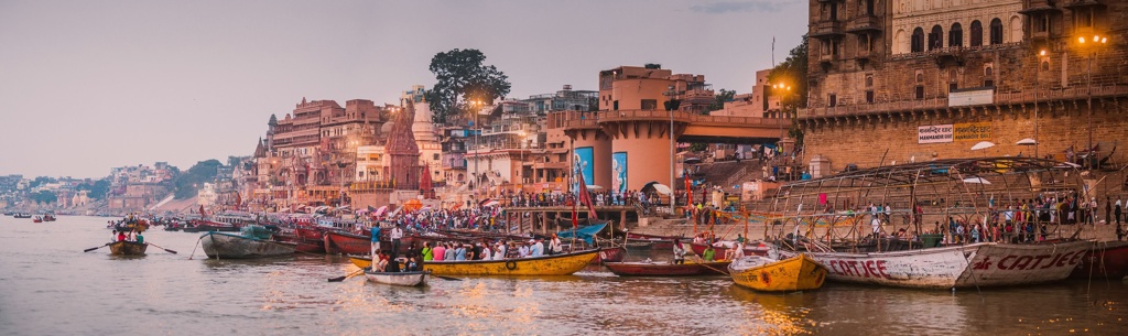 Drukke ghat aan de Ganges in Varanasi met boten en tempels bij zonsondergang, tijdens familiereis India en Nepal.