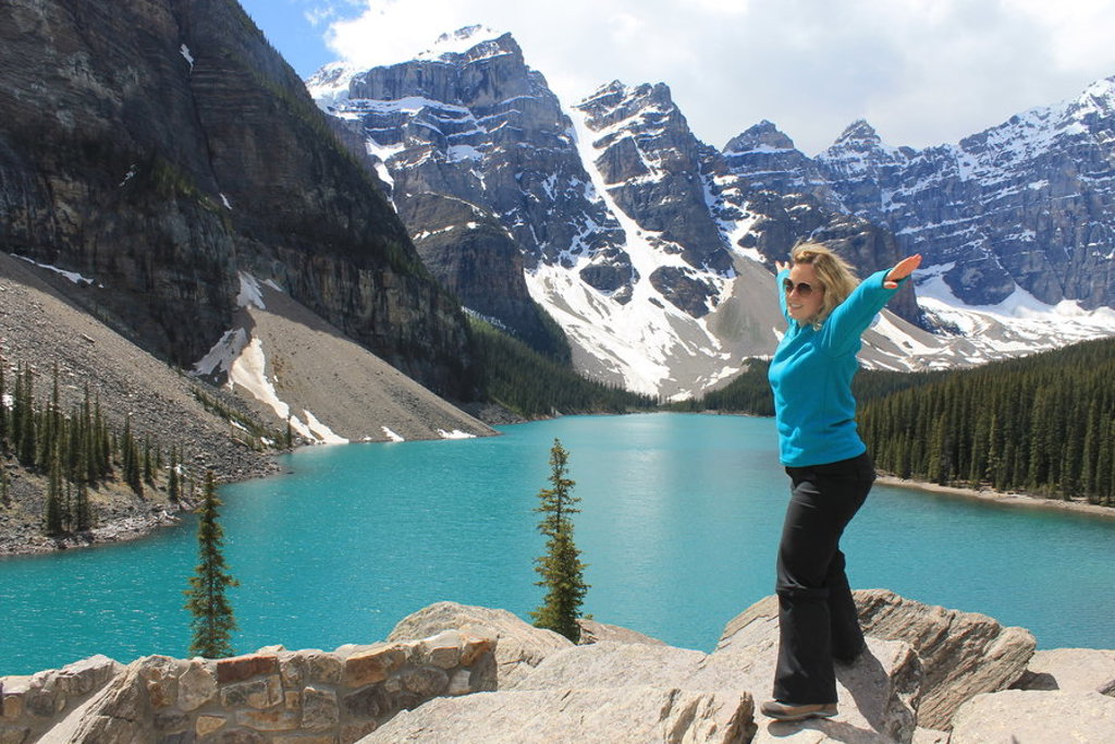Reiziger bij turquoise bergmeer in Canada West, met besneeuwde bergen op de achtergrond.