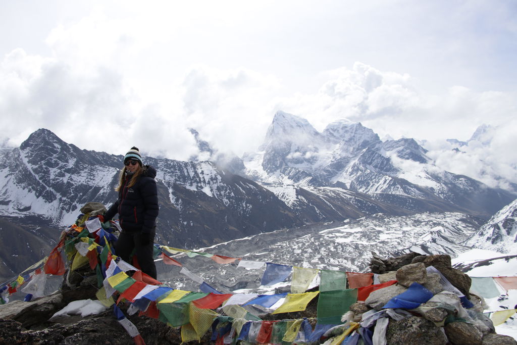 Wandelaar bij gebedsvlaggen met uitzicht op besneeuwde Himalaya-toppen tijdens groepsrondreis Nepal Everest.
