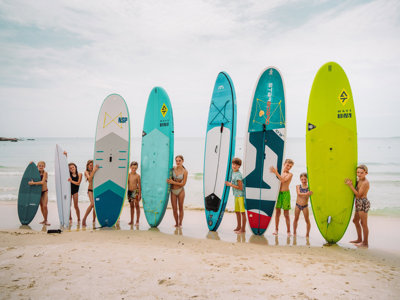 Kinderen op het strand in Thailand met surf- en SUP-boards tijdens familiereis Thailand Noord en Zuid.