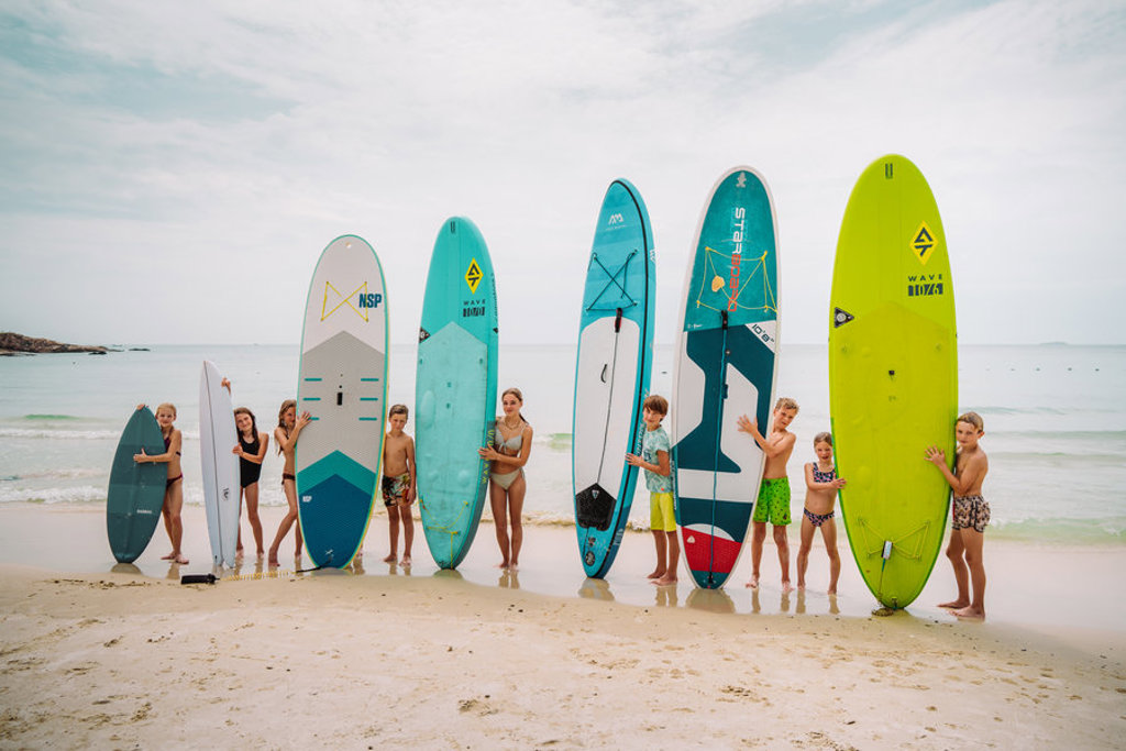 Kinderen op het strand in Thailand met surf- en SUP-boards tijdens familiereis Thailand Noord en Zuid.