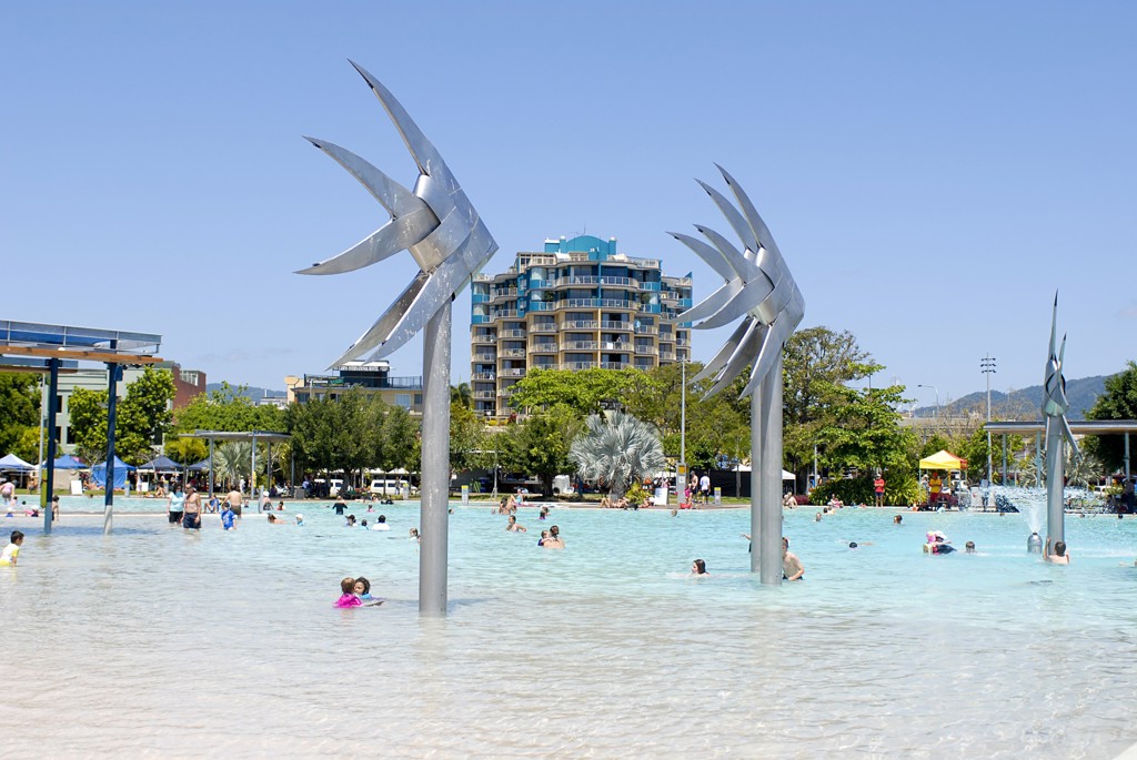Lagunezwembad met zilveren kunstwerken en spelende mensen aan de Esplanade in Cairns, Australië.