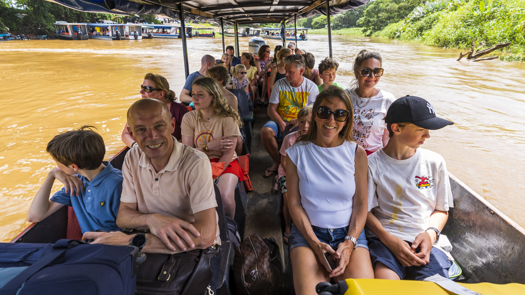 Gezinnen varen met een boot over een rivier in Costa Rica tijdens een familiereis.