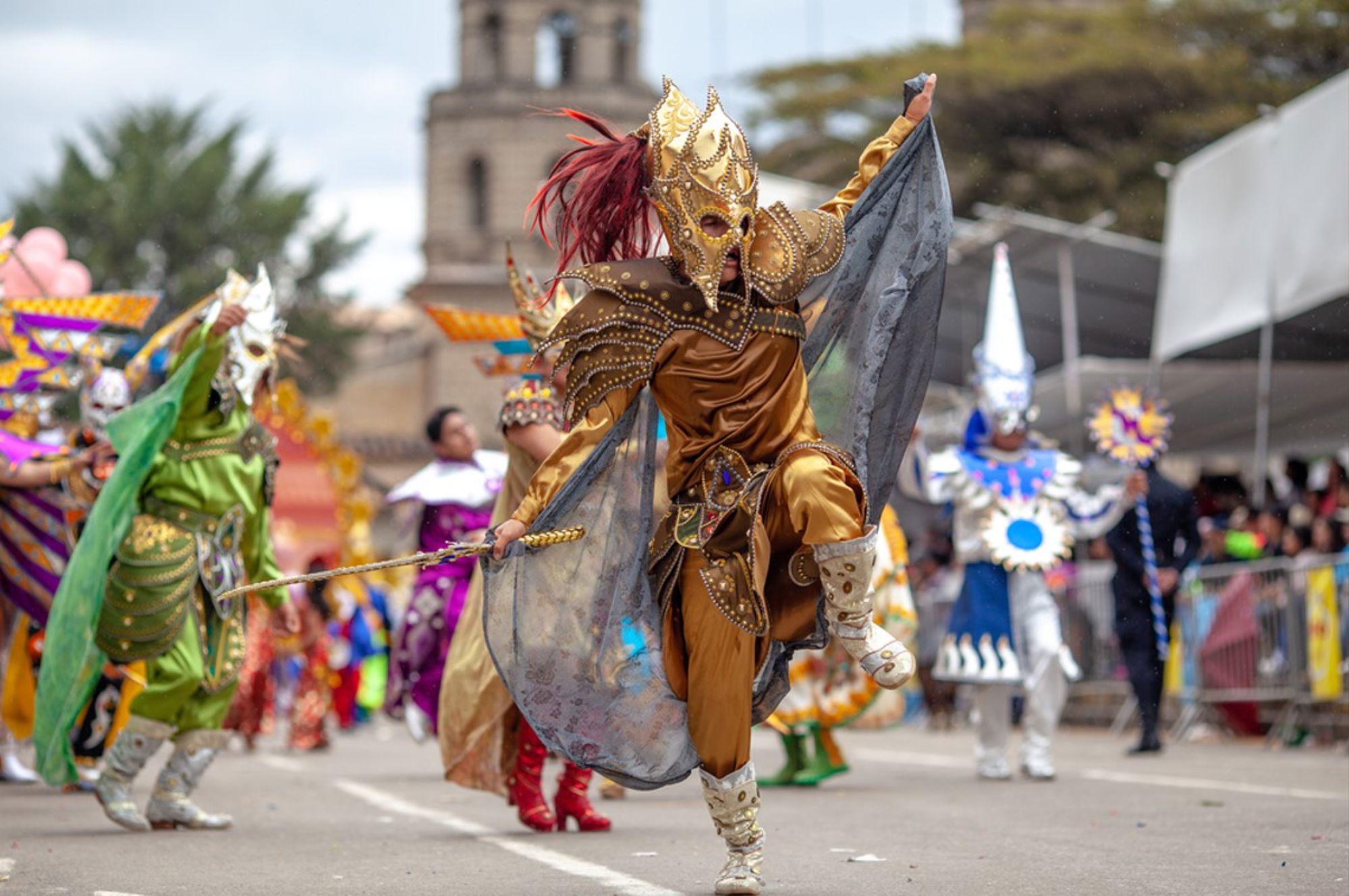 Gemaskerde danser in goudkleurig kostuum tijdens een kleurrijke straatparade in Peru.