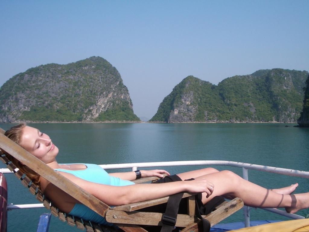 Ontspannen op het dek van een boot in Halong Bay, Vietnam, met uitzicht op kalkstenen eilanden.