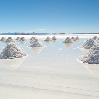 Zoutkegels op de Salar de Uyuni zoutvlakte in Bolivia, met spiegelende waterlaag en bergen in de verte.
