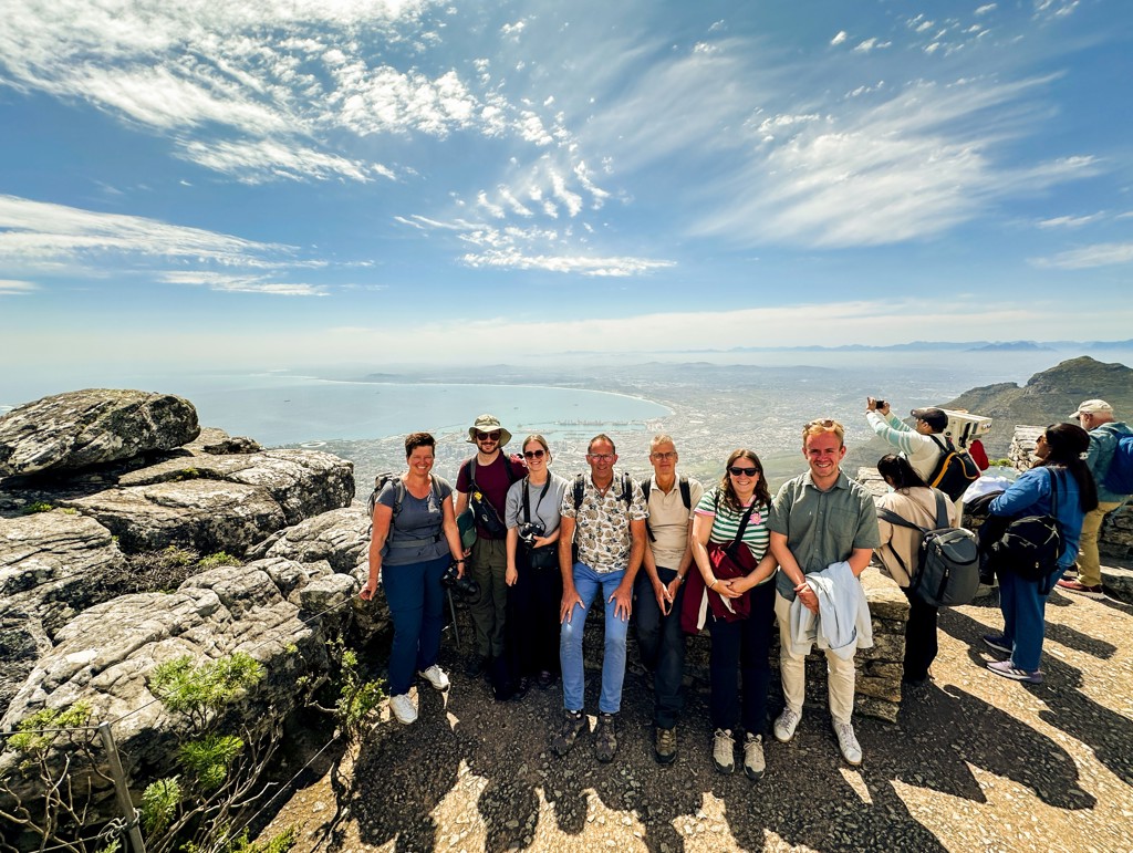 Groepsrondreis Zuidelijk Afrika: reisgroep bij uitzichtpunt op de Tafelberg, met panorama over Kaapstad en de oceaan.