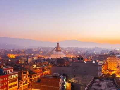 Zonsondergang boven Kathmandu met de Boudhanath-stoepa en stadslichten, Route Nepal.