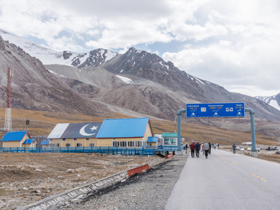 Weg op de Karakoram Highway met richtingborden naar Gilgit, omringd door besneeuwde bergen in Pakistan.