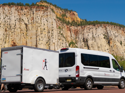 Witte bus met aanhanger in Amerika, geparkeerd voor hoge rotswand.