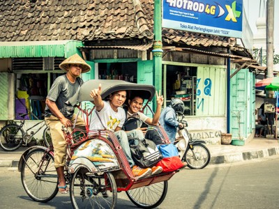 Twee reizigers in een becak in Yogyakarta, Java, tijdens de route Sumatra, Java en Bali.