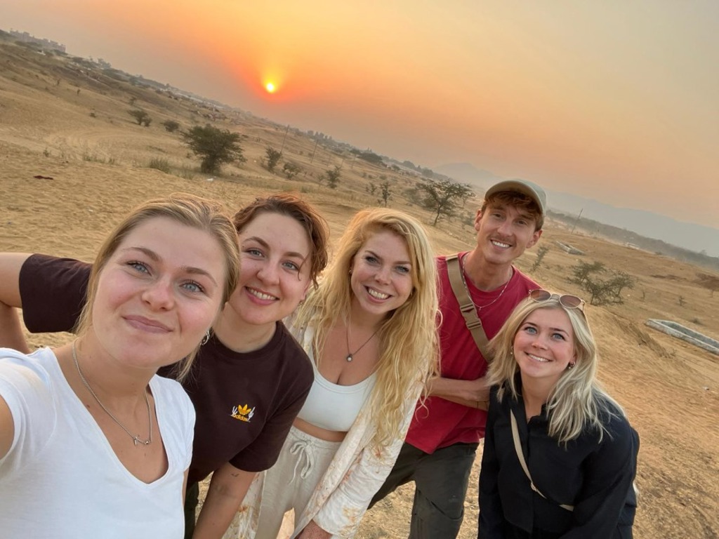 Groep jonge reizigers maakt een selfie in de woestijn bij zonsondergang tijdens een 22-35ers reis India.