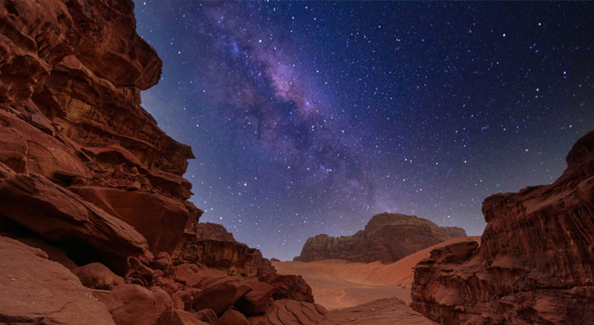 Sterrenhemel met de Melkweg boven de rotsformaties en zandduinen van Wadi Rum in Jordanië.