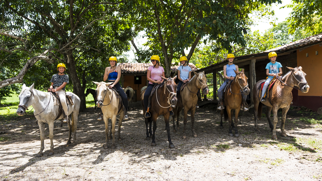 Gezin te paard op een ranch in Costa Rica tijdens een familiereis.