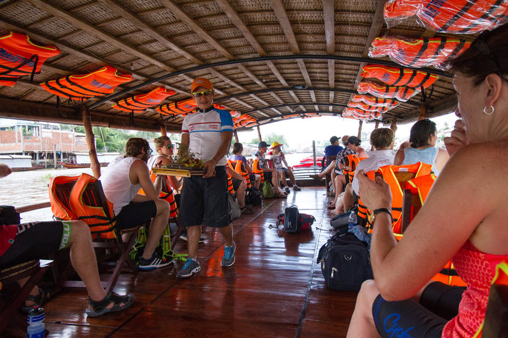 Fietsers op een rivierboot met reddingsvesten tijdens fietsvakantie Vietnam, Cambodja en Thailand.