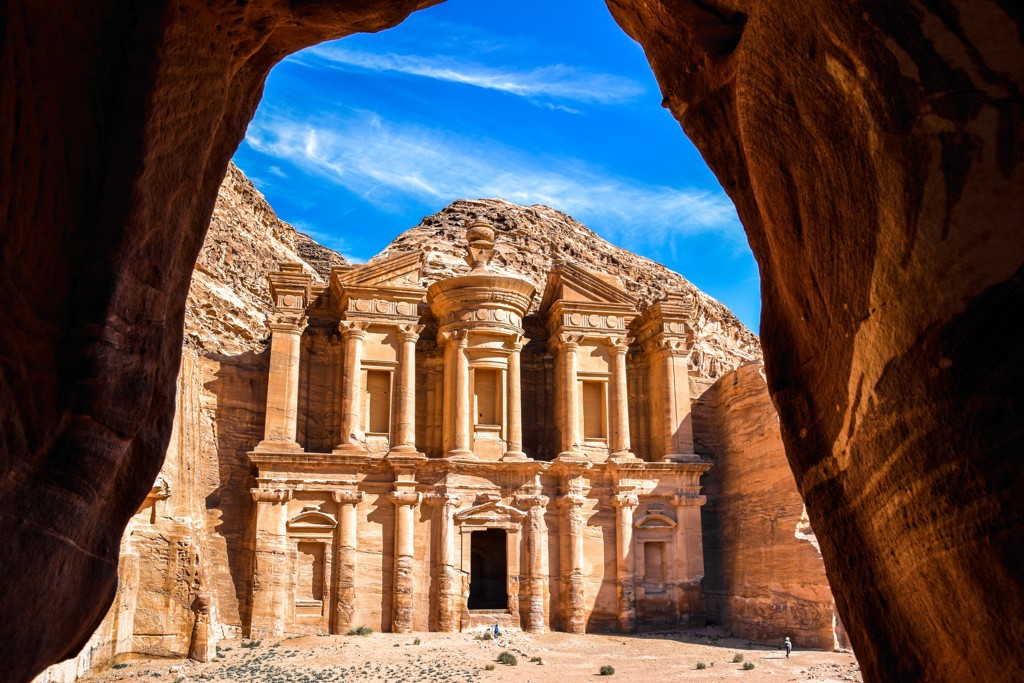 Het Klooster (Ad Deir) in Petra, Jordanië, gezien door een rotsboog onder een blauwe lucht.