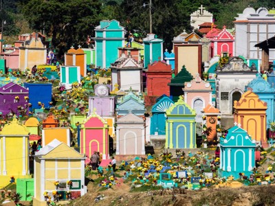Kleurrijke begraafplaats met beschilderde grafmonumenten en bloemen langs de Route Ruta Maya.