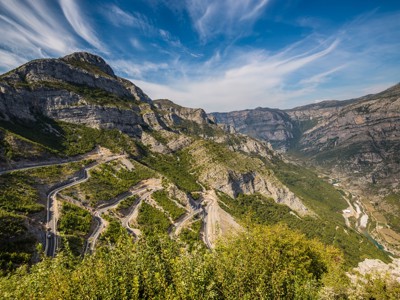 Kronkelende bergweg door een diepe kloof in de Balkan, onderdeel van de Route Balkan wandelrondreis.