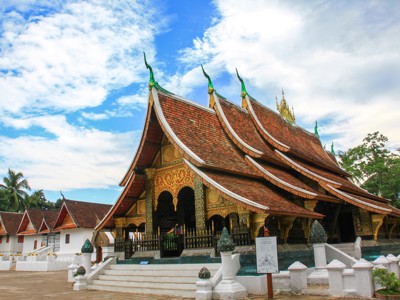 Traditionele tempel in Luang Prabang met rijk versierd dak onder een blauwe lucht.