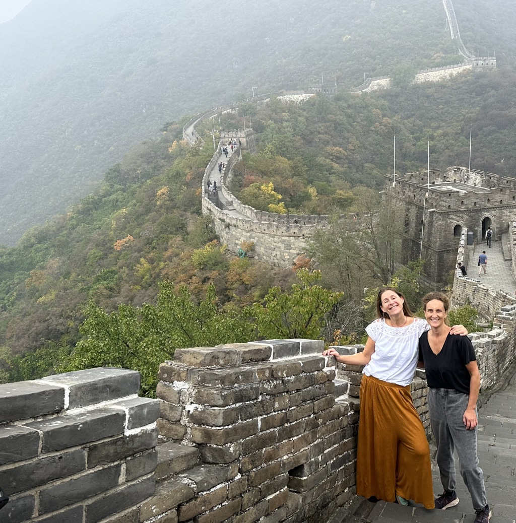 Reizigers op de Chinese Muur tijdens groepsrondreis China, met uitzicht op groene bergen en wachttoren.