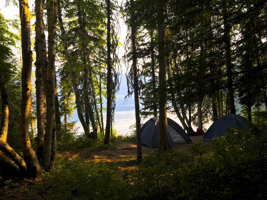 Kamperen in de Canadese Rockies: tenten in het bos aan een meer bij zonsondergang.