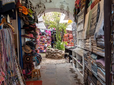 Kleurrijke marktstraat in Peru met kraampjes vol textiel, hoeden en sieraden.