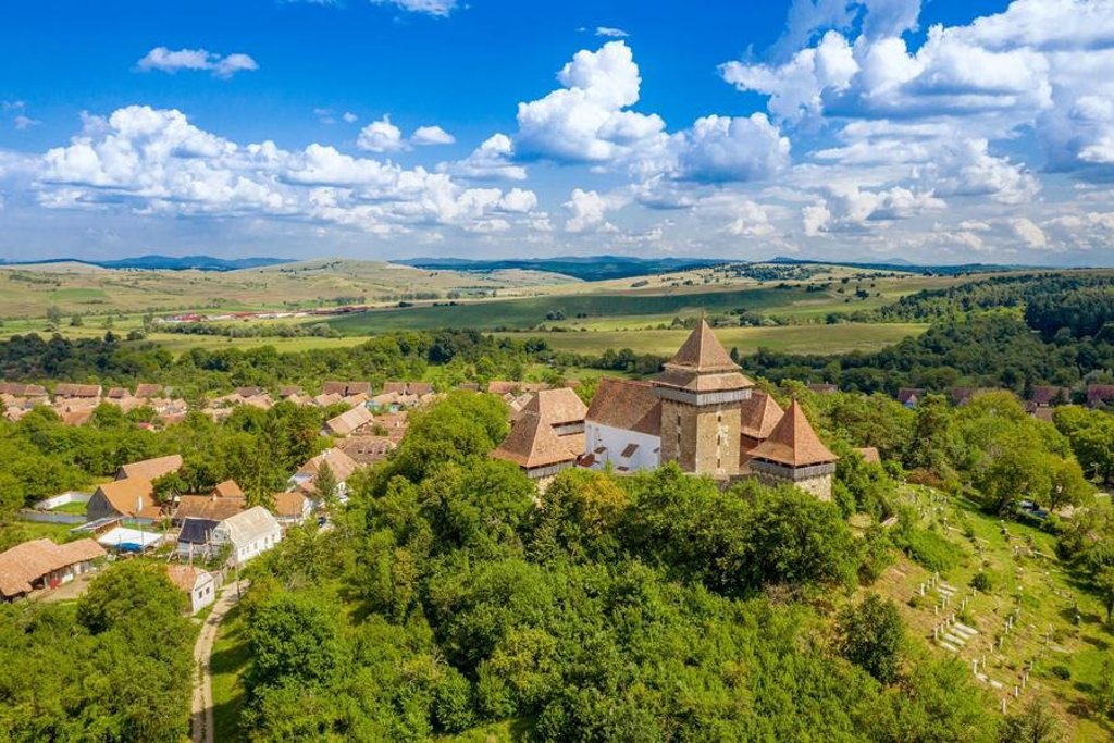 Groepsrondreis Roemenië: landschap met heuvels en bergen onder een bewolkte lucht.