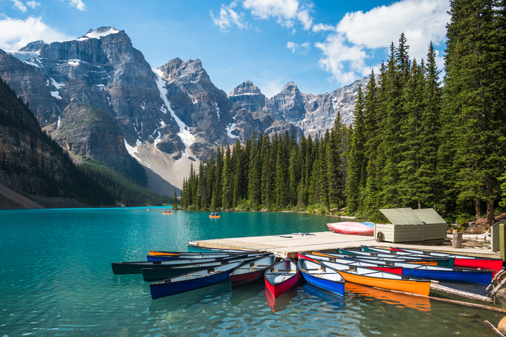 Kano’s aan de steiger op Moraine Lake in de Canadese Rockies, met bergen en dennenbos op de achtergrond.