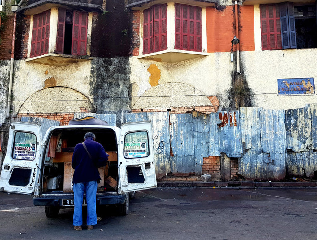 Man bij open achterdeuren van busje in straatbeeld van Madagascar tijdens groepsrondreis.