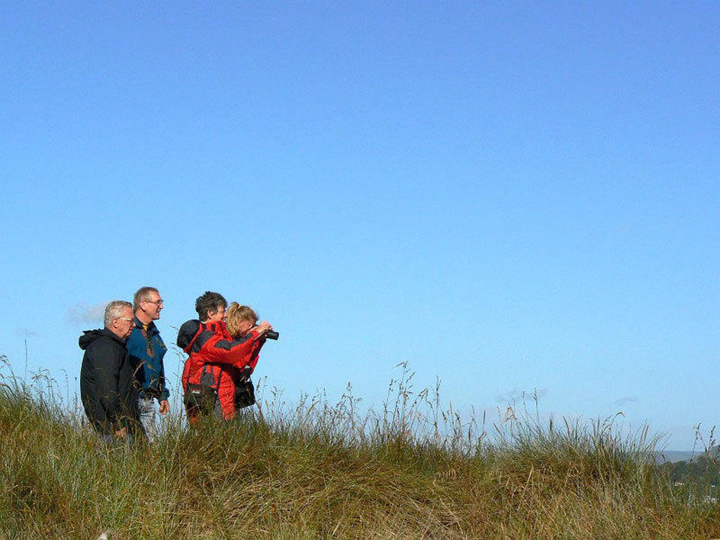 Wandelaars spotten natuur met verrekijker tijdens groepsrondreis Nieuw-Zeeland.