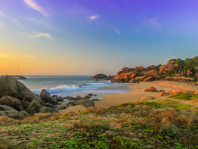 Rotsachtige kust en zandstrand bij zonsondergang langs de route in Sri Lanka.