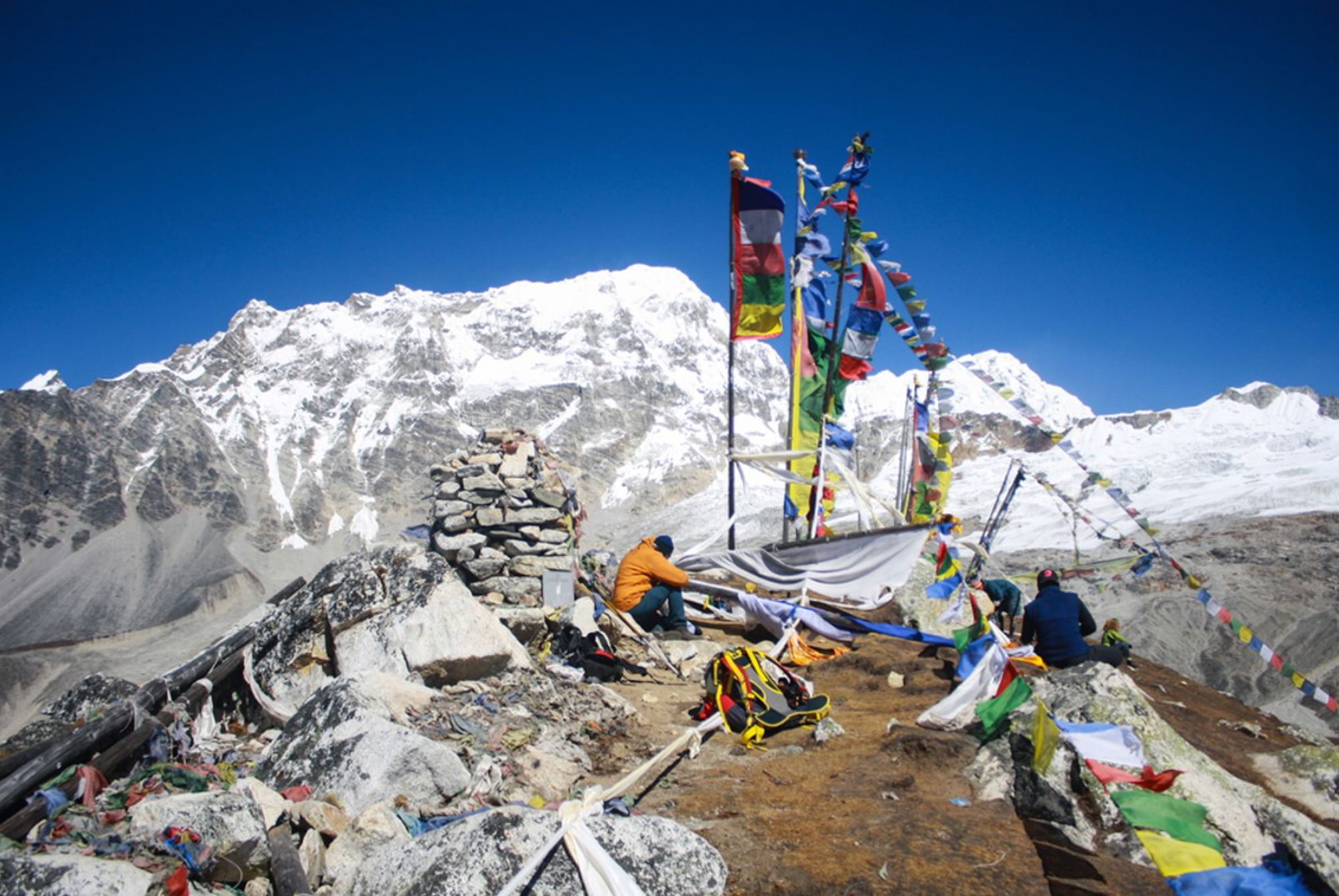 Gebedsvlaggen op een bergpas in Nepal met besneeuwde Himalaya-toppen op de achtergrond.
