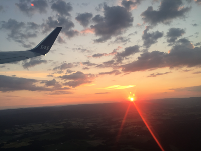 Vliegtuigvleugel boven het landschap bij zonsondergang, start van de reis naar Spitsbergen, Groenland & IJsland.