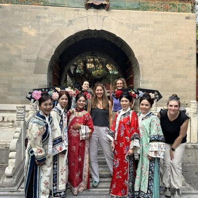 Groepsrondreis China hoogtepunten: reizigers poseren met vrouwen in traditionele kledij bij een tempelpoort.