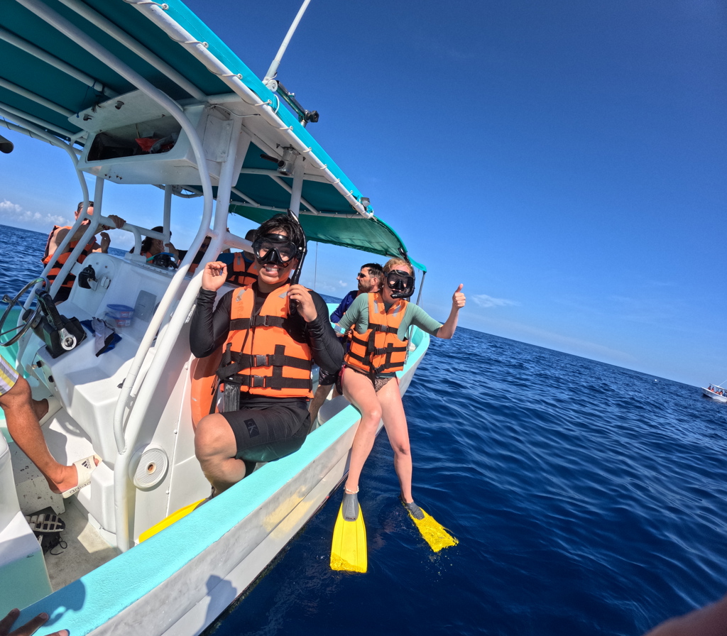 Snorkelaars met duikmaskers en zwemvliezen stappen vanaf een boot de zee in tijdens een familiereis Mexico.