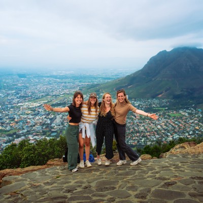 22-35ers reizen Zuid-Afrika: vriendinnengroep op uitzichtpunt met Kaapstad en Tafelberg op de achtergrond.