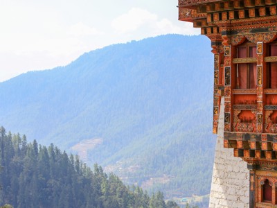 Traditioneel Bhutaans klooster met kleurrijke gevel, met uitzicht op beboste Himalaya-bergen tijdens de route Sikkim en Bhutan.